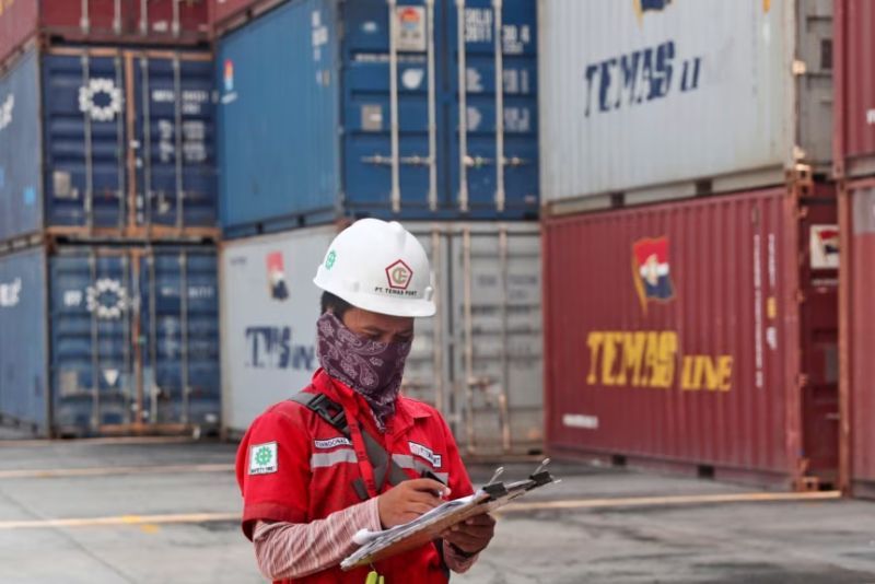 Seorang pekerja sedang mencatat data dekat tumpukan peti kemas di pelabuhan Tanjung Priok