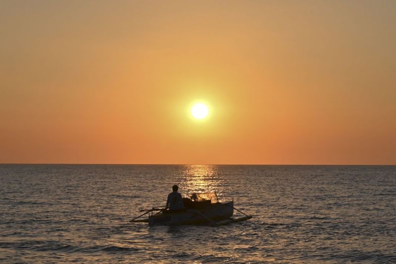 Nelayan Filipina berlayar saat matahari terbenam di pantai Bacnotan, provinsi La Union, wilayah Filipina yang menghadap ke Laut China Selatan.(AFP/ROMEO GACAD)