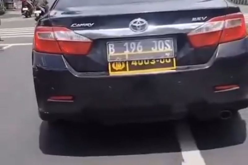 Sebuah mobil Toyota Camry berwarna hitam tertangkap kamera menggunakan pelat ganda, yakni pelat sipil dan pelat dinas Polri.(DOK. Tangkap layar akun X @Heraloebss)