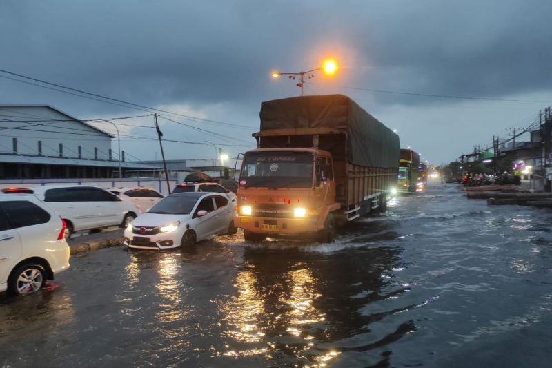 Sejumlah kendaraan melintas di Pantura Kecamatan Sayung, Kabupaten Demak, Jawa Tengah dalam kondisi banjir rob, Minggu (6/4/2025) malam.(KOMPAS.COM/NUR ZAIDI)