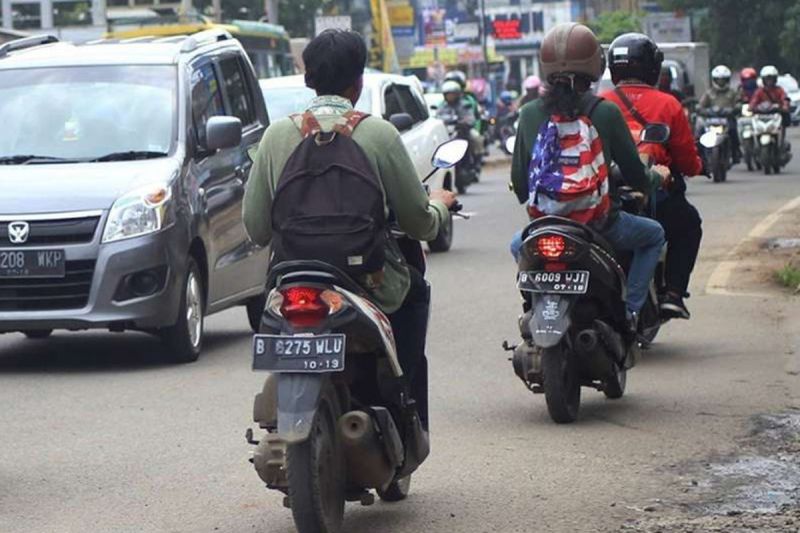 Ilustrasi mengendarai motor sambil gendong tas punggung.(kompas.com)