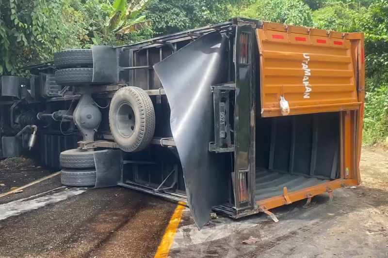 Sebuah truk kontainer bermuatan paket terguling dan menutup total akses jalan Trans Sulawesi setelah diduga mengalami rem blong, Rabu (14/5/2025).(KOMPAS.COM/JUNAEDI)