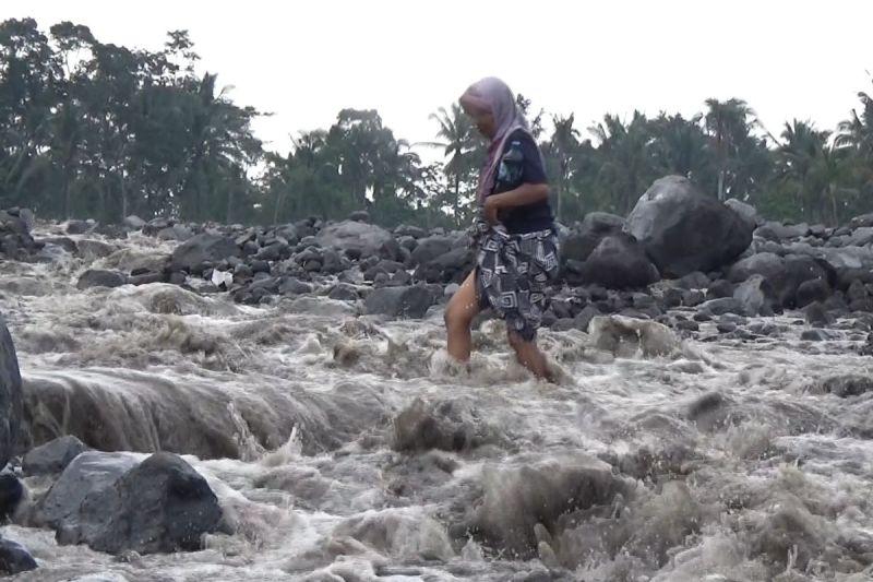Warga sebrangi aliran lahar hujan Gunung Semeru di Sungai regoyo, Kamis (15/5/2025)(KOMPAS.com/MIFTAHUL HUDA)