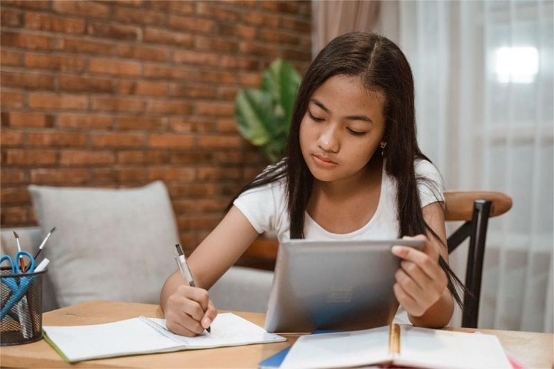 siswi terlihat fokus belajar di meja dengan catatan