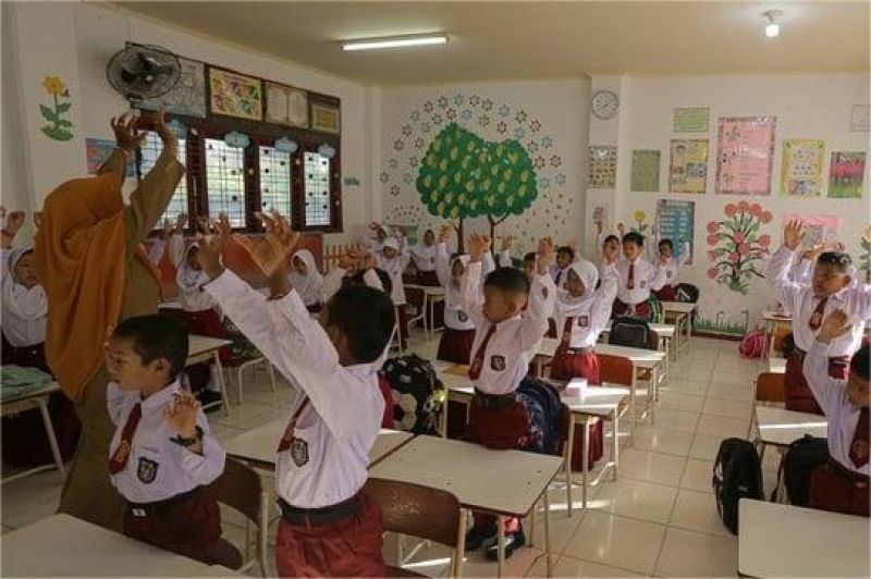 guru dan siswa berdiskusi dalam kelas dengan suasana interaktif dan ceria