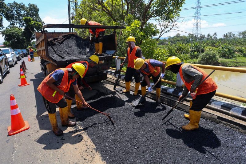 ilustrasi petugas memperbaiki jalan nasional jelang arus mudik Idul Adha