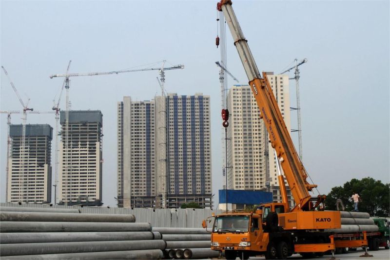 foto pembangunan apartemen baru di kota besar dengan alat berat dan pekerja konstruksi