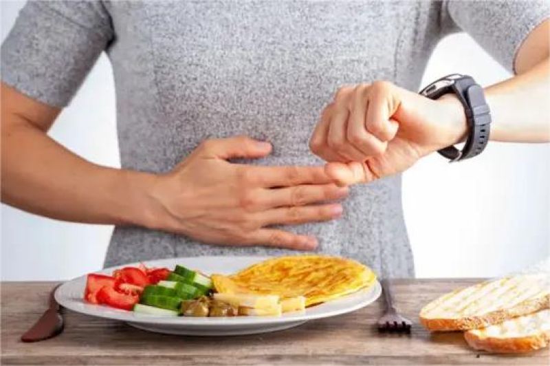 ilustrasi orang melihat jam sambil menahan lapar sebagai bagian dari intermittent fasting