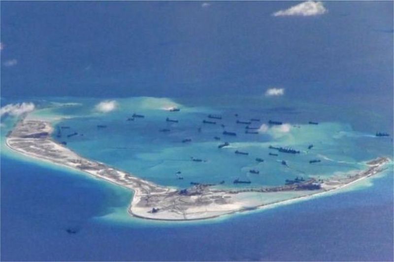 kapal patroli militer berlayar di perairan Laut Cina Selatan dengan latar pulau buatan