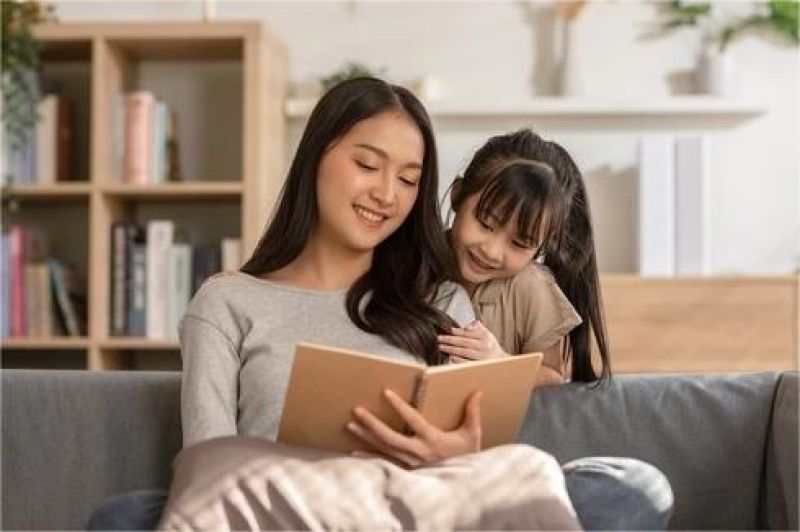 anak kecil sedang membaca buku cerita bersama orang tua di ruang keluarga