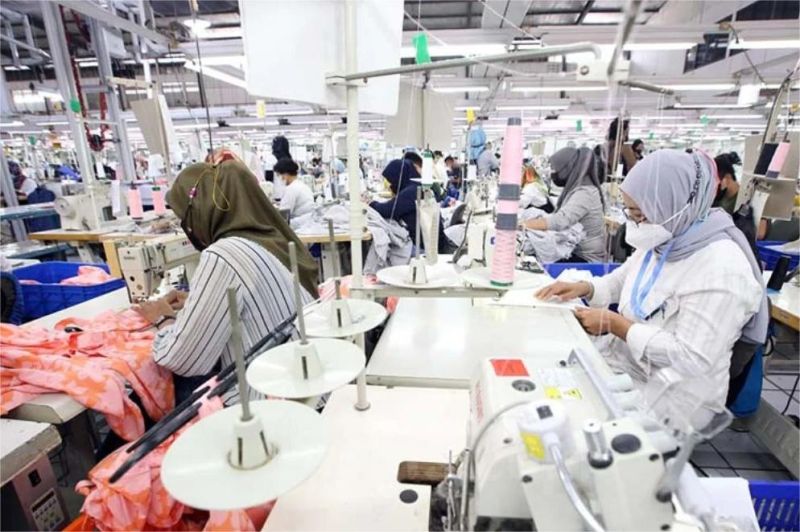 foto buruh tekstil sedang bekerja di jalur produksi pabrik yang mulai sepi