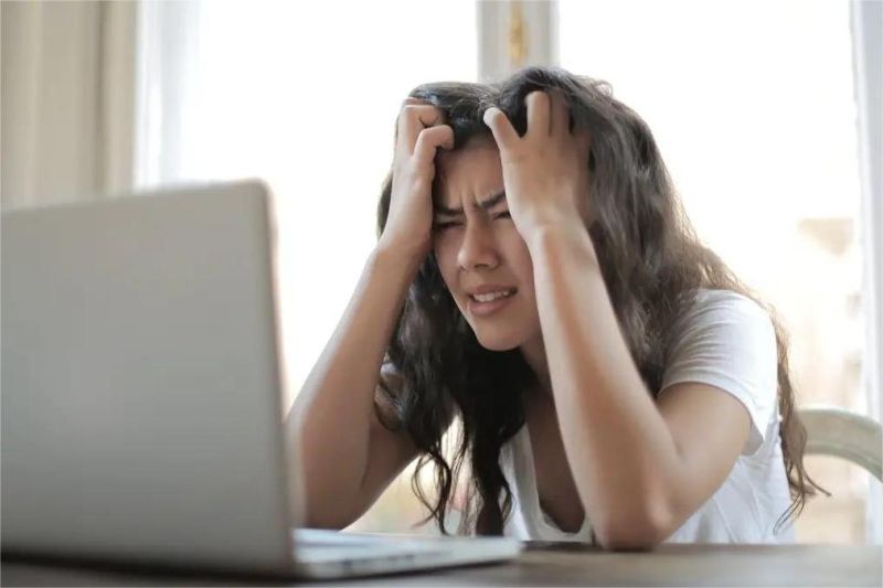 pekerja muda kelelahan di depan laptop dengan ekspresi stres di ruang kerja rumah