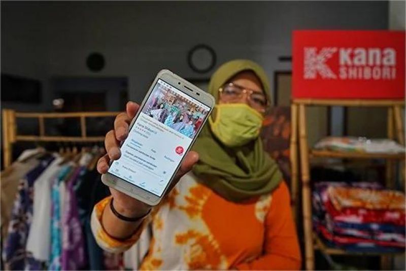 pelaku UMKM lokal sedang mengakses aplikasi pembiayaan digital melalui smartphone