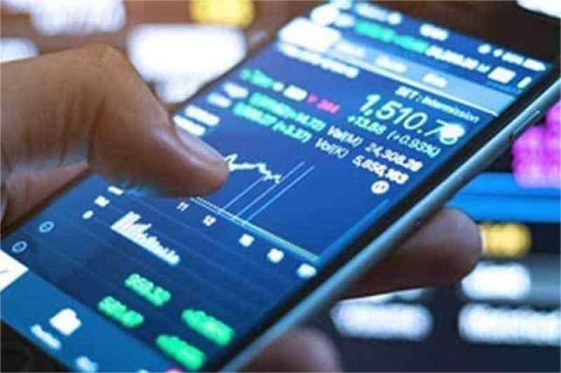 ilustrasi tangan memegang smartphone dengan layar investasi online dan tanda peringatan