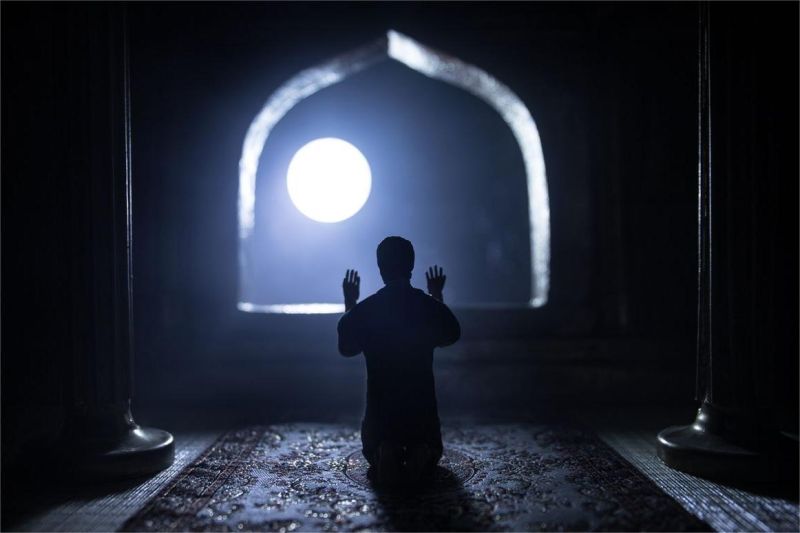 seseorang duduk merenung di bawah langit malam sambil berdoa