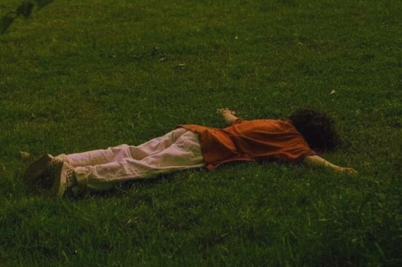 seorang laki-laki sedang merebahkan badan di padang rumput untuk mencari kebahagiaan dan ketenangan