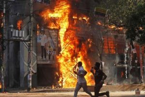 Pria berlari melewati pusat perbelanjaan yang dibakar oleh pengunjuk rasa selama unjuk rasa menentang Perdana Menteri Sheikh Hasina dan pemerintahannya yang menuntut keadilan bagi para korban yang tew