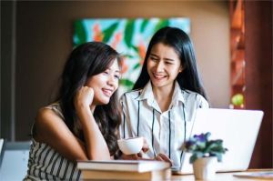 anak muda tersenyum sambil memegang hadiah kecil di meja kafe sebagai bentuk self-reward