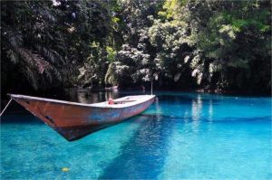 Permukaan air jernih Danau Labuan Cermin memantulkan langit dan pepohonan