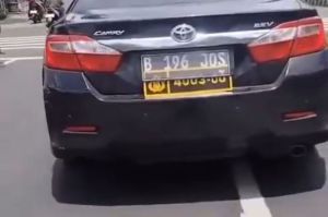 Sebuah mobil Toyota Camry berwarna hitam tertangkap kamera menggunakan pelat ganda, yakni pelat sipil dan pelat dinas Polri.(DOK. Tangkap layar akun X @Heraloebss)