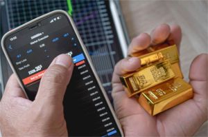 anak muda melihat grafik investasi emas di layar smartphone