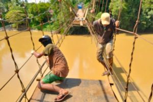 Pekerja sedang memperbaiki jembatan gantung penghubung Desa Simpang Limbur Merangin dengan Desa Limbur Merangin yang terputus. (Dok: Istimewa).(KOMPAS.COM/ARYO TONDANG)