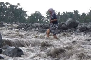 Warga sebrangi aliran lahar hujan Gunung Semeru di Sungai regoyo, Kamis (15/5/2025)(KOMPAS.com/MIFTAHUL HUDA)