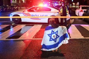 Seorang pria memakai bendera Israel duduk di tengah jalan lokasi penembakan di Museum Yahudi Washington DC, Amerika Serikat, Kamis (22/5/2025). Penembakan di Washington ini menewaskan dua staf Kedutaa