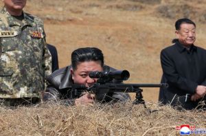 Pemimpin Tertinggi Korea Utara Kim Jong Un (tengah) saat membidik sasaran melalui teropong senapan jarak jauh ketika mengunjungi markas latihan Angkatan Bersenjata Rakyat Korut