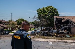 Seorang polisi berdiri di depan sebuah rumah yang rusak setelah sebuah pesawat kecil jatuh di permukiman warga dan membakar sejumlah rumah dan kendaraan pada Kamis (22/5/2025) di San Diego