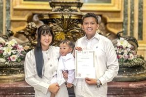 Erlinda Aji Ayuningrum menggendong Damian Orlin Baskara di dampingi Daniel Oscar Baskoro usai penerimaan Sakramen Baptis bagi Damian di Basilika Santo Petrus, Vatikan, Senin (26/5/2025).