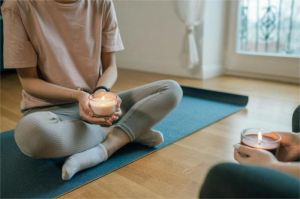 anak muda sedang meditasi santai di kamar dengan lilin aromaterapi menyala