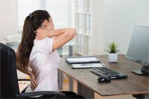seorang pekerja remote duduk membungkuk lama di depan laptop, menggambarkan risiko gaya hidup sedentari