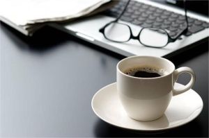 secangkir kopi di meja kerja dengan laptop menyala, simbol konsumsi berlebihan saat stres