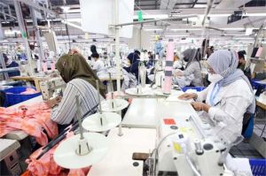 foto buruh tekstil sedang bekerja di jalur produksi pabrik yang mulai sepi
