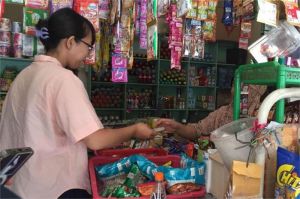 seorang pengusaha kecil sedang melayani pelanggan di toko kelontong
