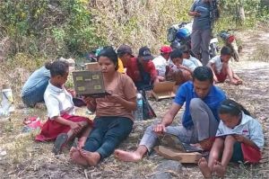 warga daerah terpencil menggunakan internet dengan sinyal lemah di alam terbuka