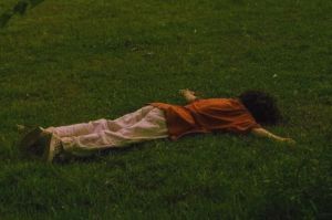 seorang laki-laki sedang merebahkan badan di padang rumput untuk mencari kebahagiaan dan ketenangan